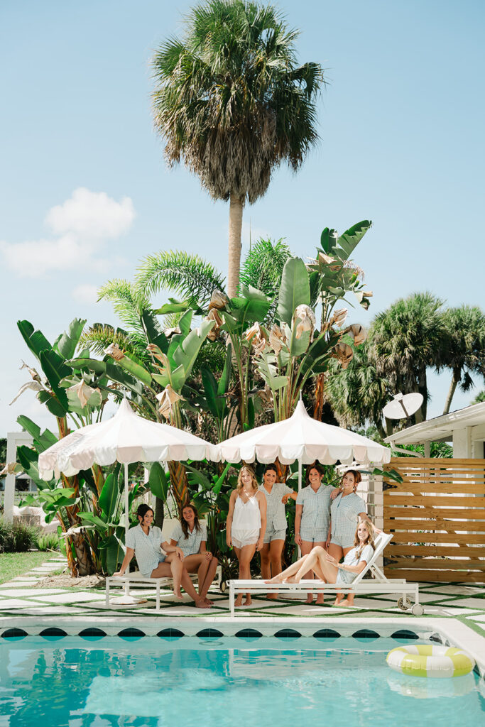 Bride and bridesmaids gathered beside a tropical pool
